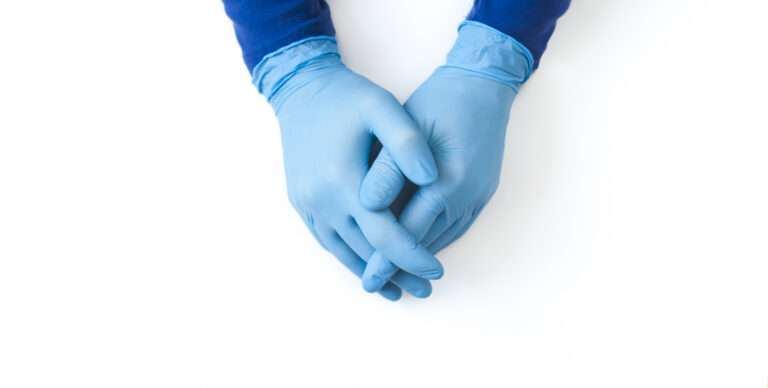 Blue Nitrile gloves banner. Hands of a medic in the blue latex gloves on white table.